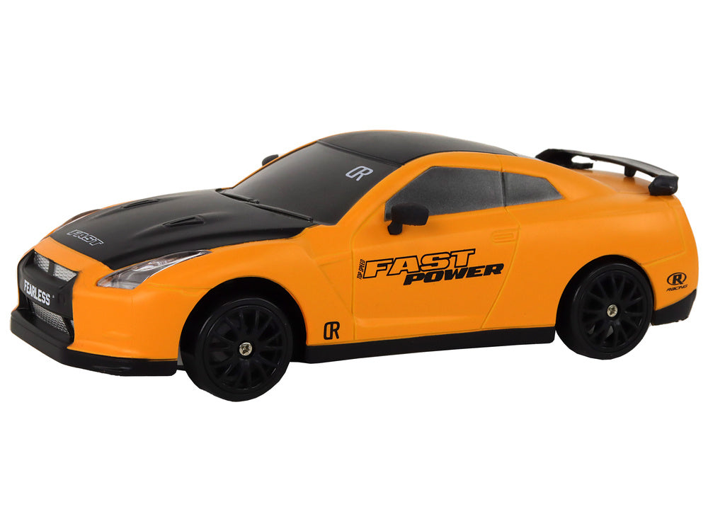 oranža rotaļu drifta mašina ar melniem riteņim uz balta fona