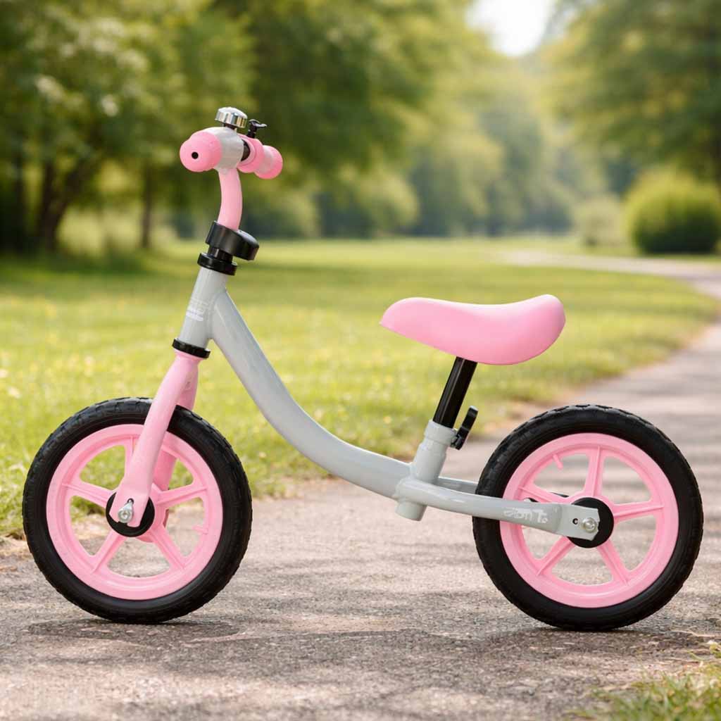 Pelēki rozā bērnu balansa velosipēds uz celiņa parkā