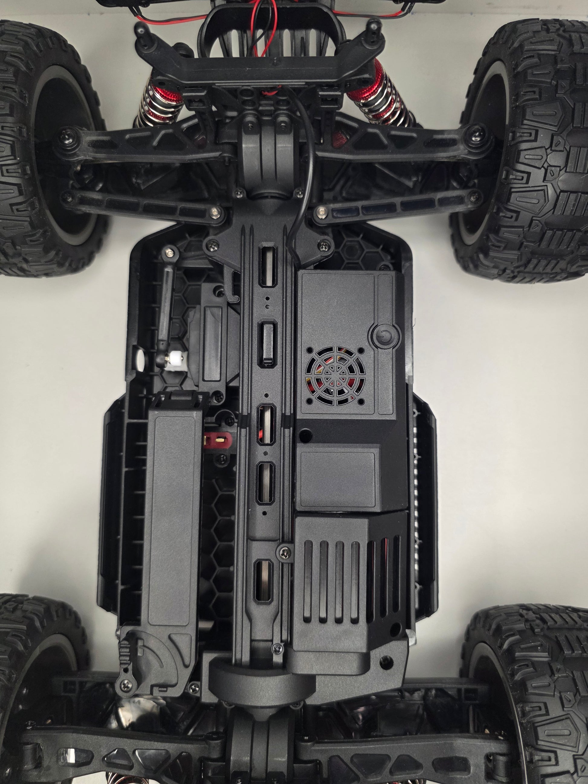 RC mašīnas Titan-X apakšpuse ar aizsargpannas konstrukciju un amortizatoriem.