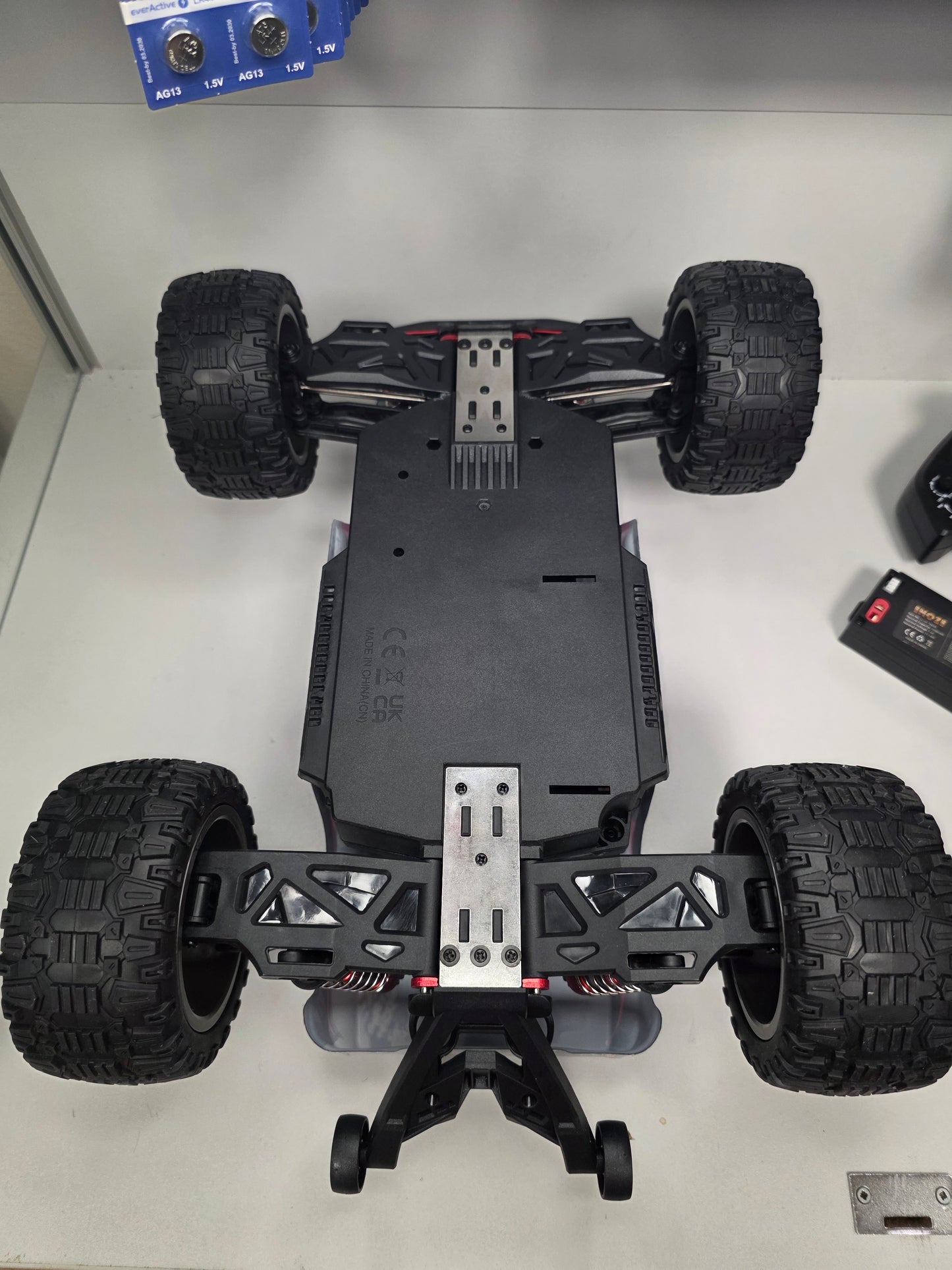 RC mašīna Titan-X apakšskats ar metāla stiprinājumiem un lielām bezceļa riepām