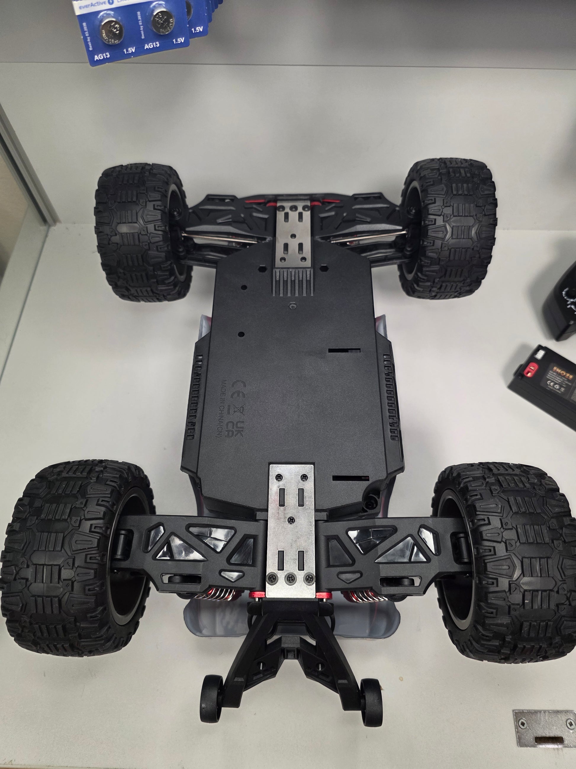 RC mašīna Titan-X apakšskats ar metāla stiprinājumiem un lielām bezceļa riepām