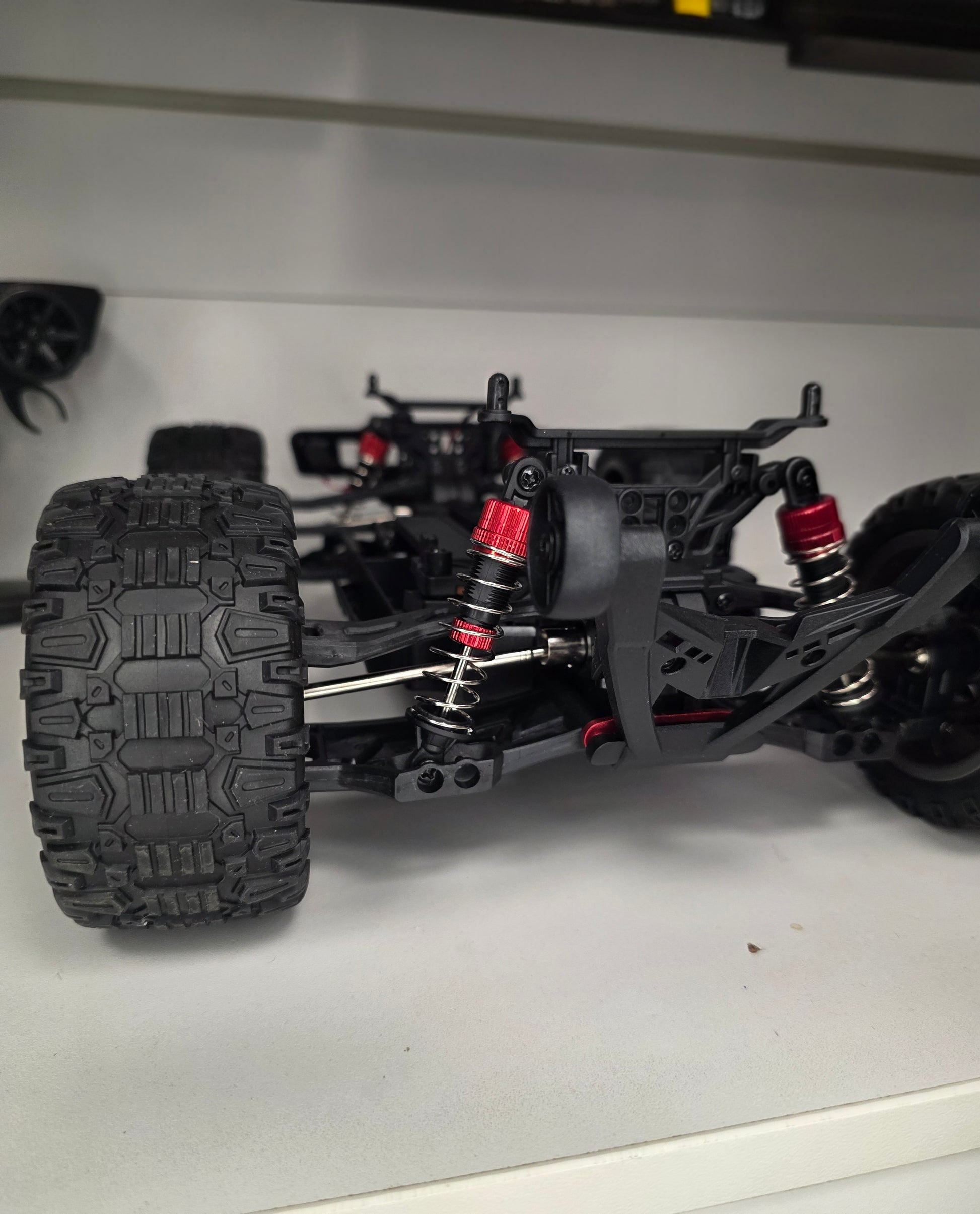 RC mašīnas Titan-X šasijas tuvplāns ar lieliem bezceļa riteņiem un amortizatoriem