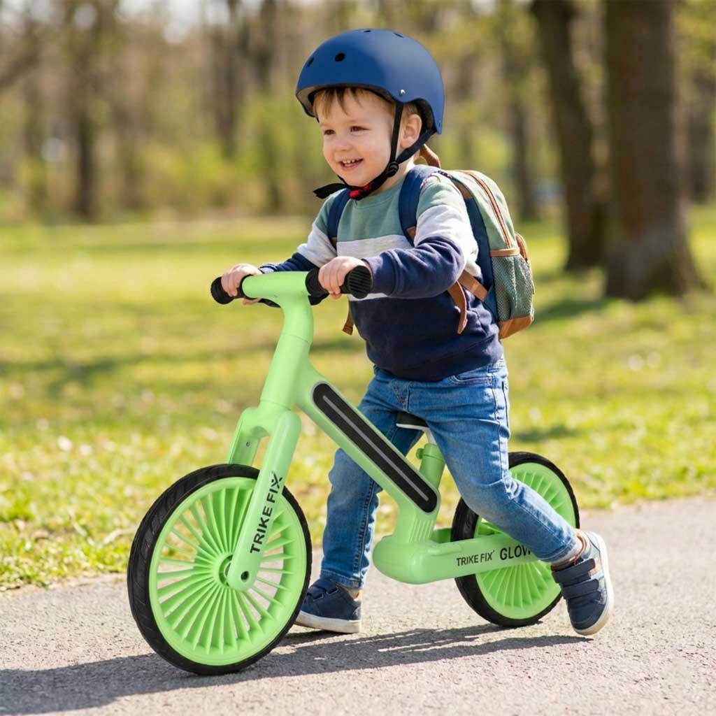 bērns brauc ar Trike Fix Glow līdzsvara velosipēdu zaļā krāsā parkā