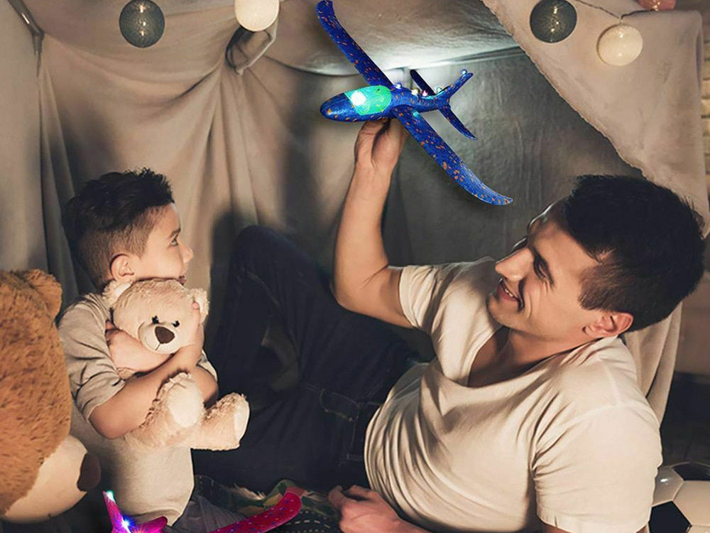 Bērns un pieaugušais spēlējas ar putu planieri ar LED gaismām mājas teltī