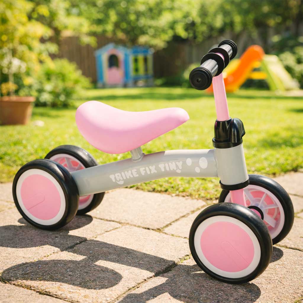 Četrriteņu balansa velosipēds bērniem pelēki rozā krāsā āra vidē uz bruģa