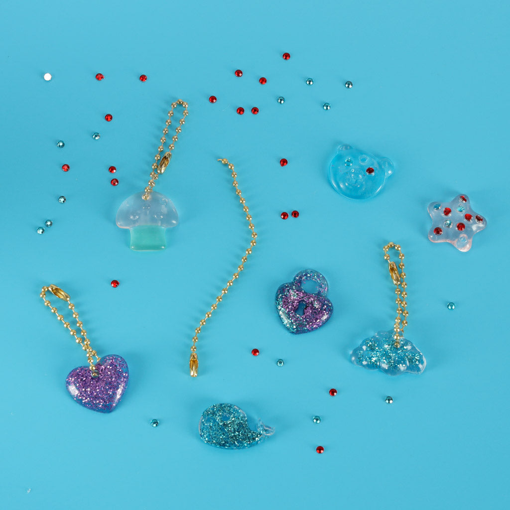 Ar Magic Box komplektu izgatavotie piekariņi ar mirdzumiem un ķēdītēm uz zilas virsmas