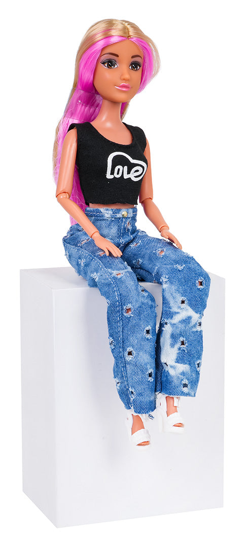 Modes lelle ar rozā matiem, melnu topiņu un džinsiem, sēžot uz balta kubusa