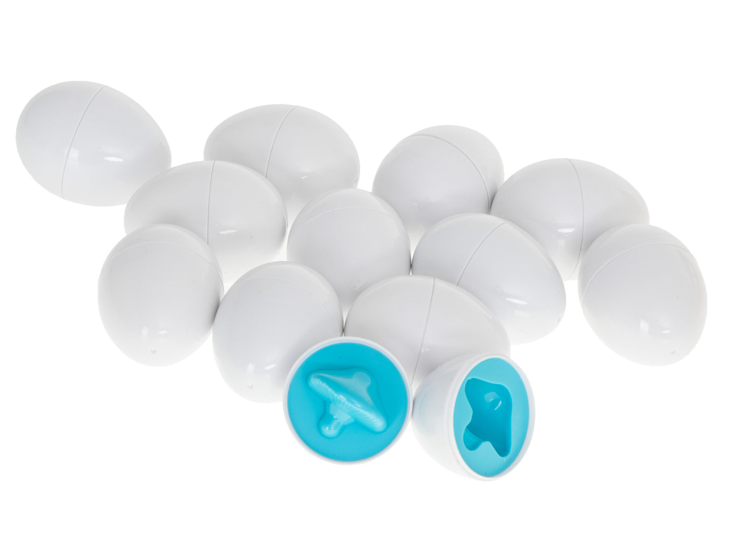 Baltas Montessori šķirošanas olas, no kurām divas atvērtas un redzamas zilas sēnes formas detaļas