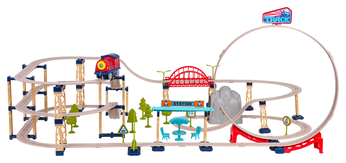 Daudzlīmeņu rotaļu dzelzceļa trase ar tiltiem, tuneli, staciju un lielu 360° cilpu, pa kuru brauc sarkans rotaļu vilciens.