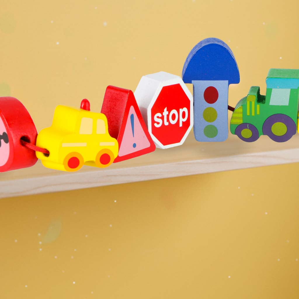 Uz aukliņas savērtas koka transporta un ceļa zīmju figūriņas uz koka malas tuvplānā