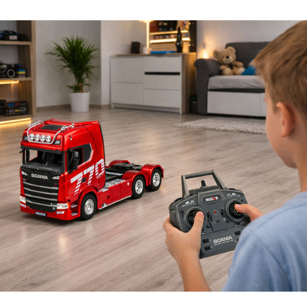 Zēns vada sarkanu tālvadības vilcēju Scania 770S ar pulti